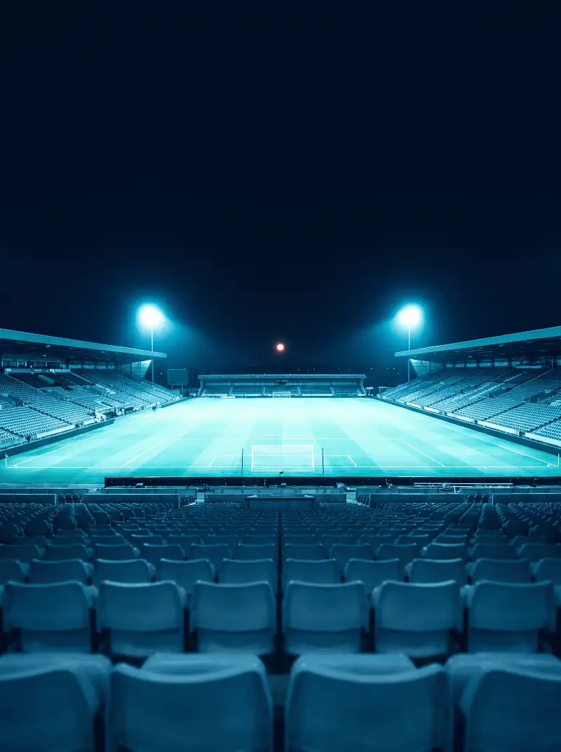Stade de football éclairé la nuit, vu depuis les tribunes